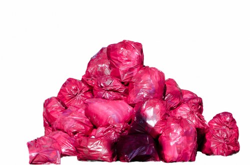 A large pile of bright pink plastic rubbish bags, tightly knotted at the top, stacked on top of each other against a plain white background. The bags are made from shiny, crinkled plastic material, with some appearing slightly stretched or bulging from contained rubbish. The pile shows varying sizes, with the bags arranged haphazardly, and the topmost bags forming a rounded, uneven mound. The scene provides a clear view of the compacted plastic waste, indicative of general rubbish or waste collection in an urban environment, possibly associated with waste disposal or rubbish removal services such as those offered by Office Clearance Leytonstone, a company operating within the local postcode area near Leytonstone. The plain background emphasizes the plastic waste, highlighting the need for proper rubbish disposal or recycling.